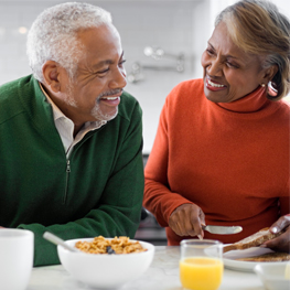 Picture of a happy senior couple, talking and laughing while enjoying breakfast